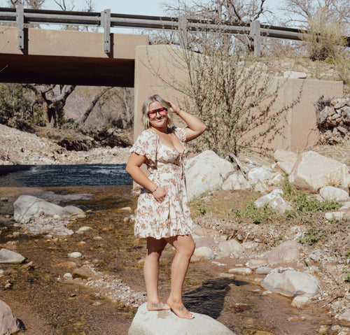Woman in a horse dress standing by a stream with a bridge in the background