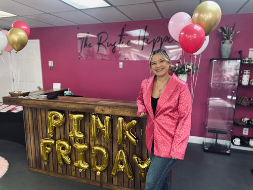 Woman standing next to a counter with 'Pink Friday' decorations in a pink-themed room.