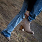 Person wearing blue jeans and beige boots on a natural background