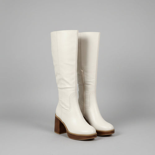 Pair of white knee-high boots with brown block heels on a gray background