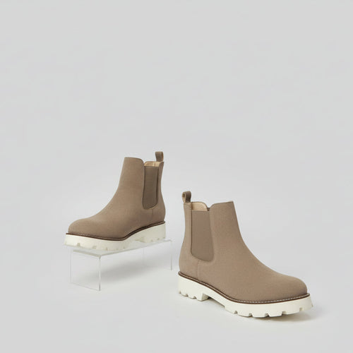 Brown Chelsea boots on a white surface