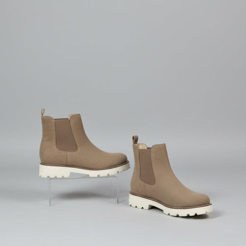 Brown Chelsea boots on a white surface