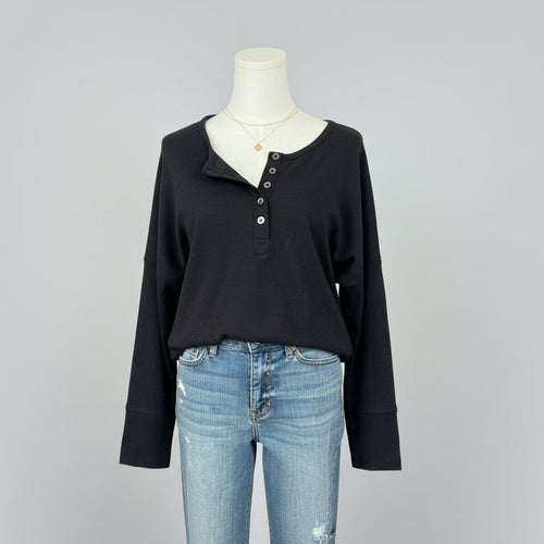 Mannequin wearing a black long-sleeve shirt and blue jeans with a white background