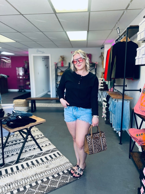 women wearing black top and shorts holding a purse in store setting