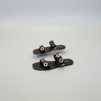 Black sandals with gold accents on a light gray background