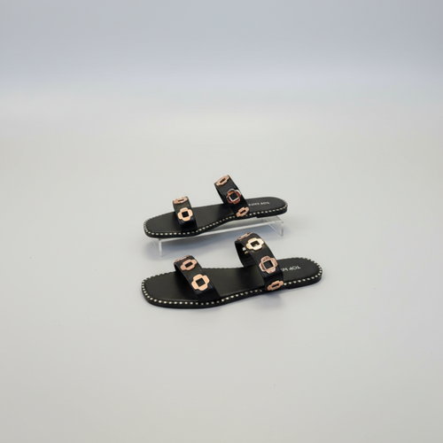 Black sandals with gold accents on a light gray background