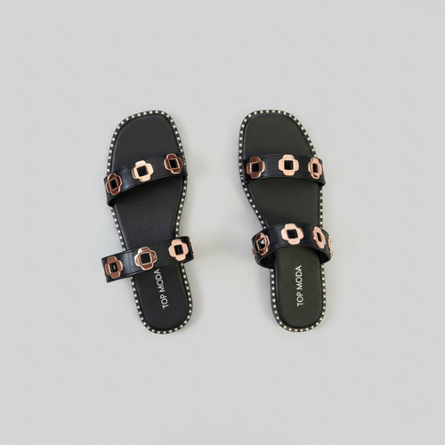 Black sandals with gold accents on a light gray background