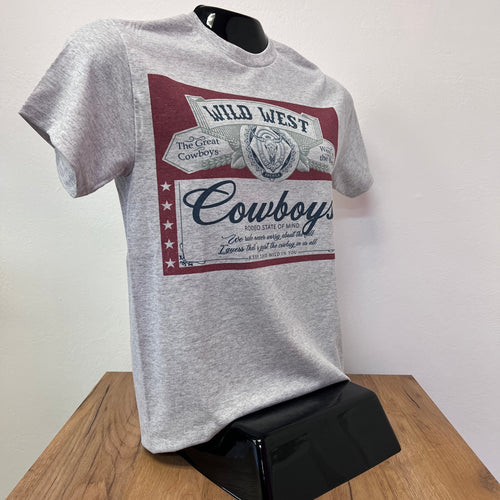 Gray t-shirt with 'Wild West Cowboys' design on a white surface with a wooden edge.
