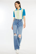 Woman wearing a colorful top and ripped jeans on a white background