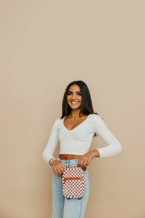 Woman holding a checkered bag against a beige background