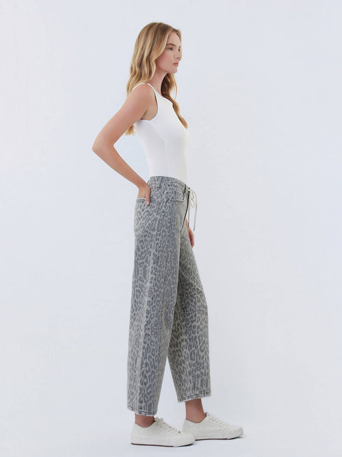 Woman wearing a white tank top and patterned pants on a light gray background