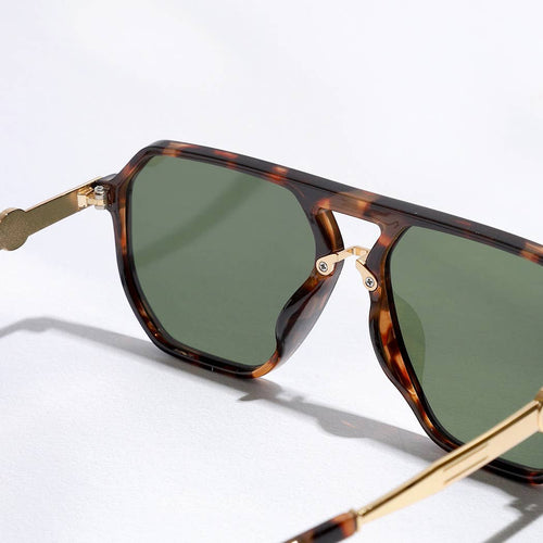 Tortoiseshell sunglasses with gold accents on a light gray background