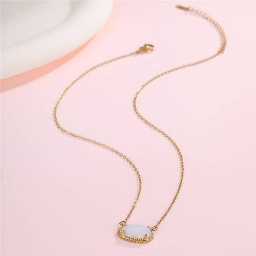 Gold necklace with a light blue pendant on a pink background