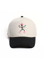 A baseball cap with an off-white crown and a black curved brim, featuring an embroidered skeleton wearing a pink hat and boots on the front.