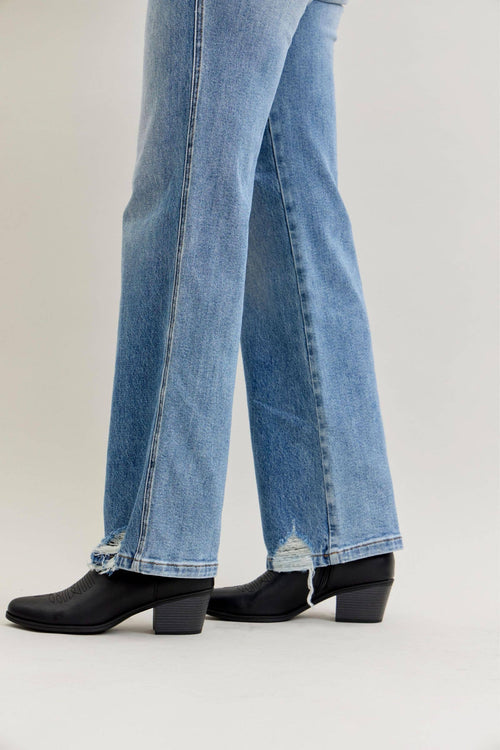 Blue jeans worn with black boots on a light gray background