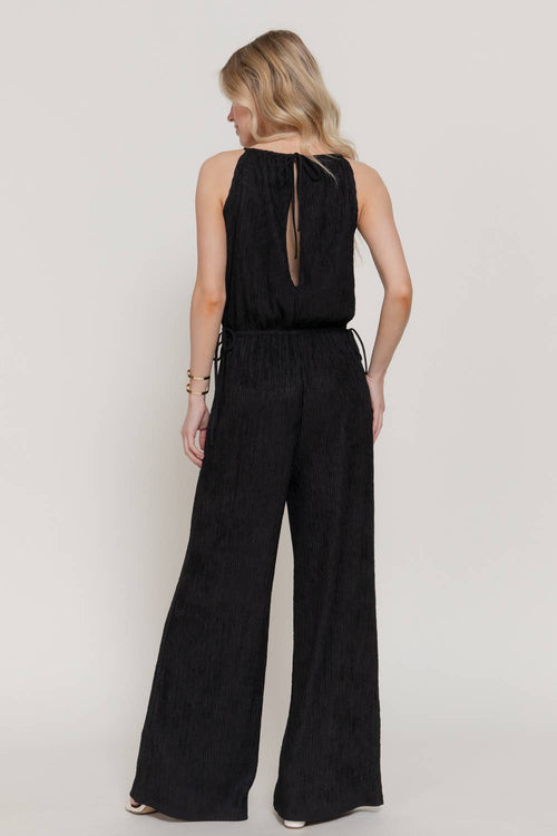 Woman wearing a black jumpsuit on a plain background
