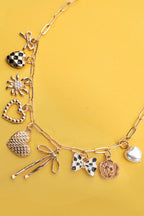 Gold necklace with various charms on a yellow background