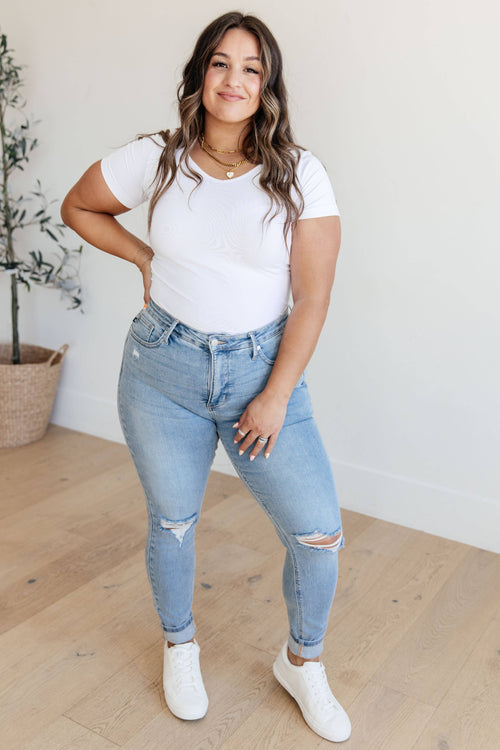 Woman wearing a white t-shirt and light blue jeans indoors.