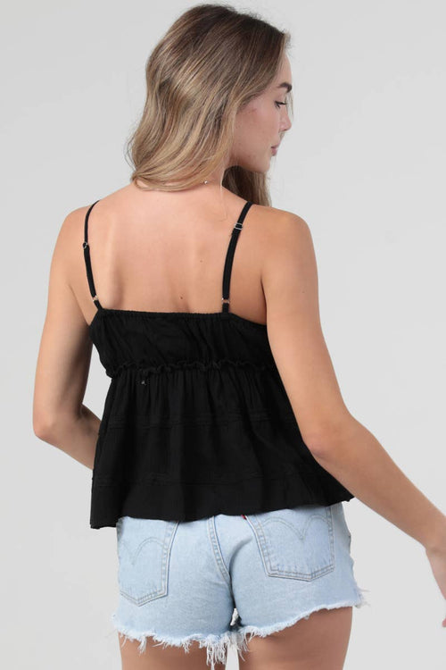 Woman wearing a black top and light blue denim shorts on a plain background
