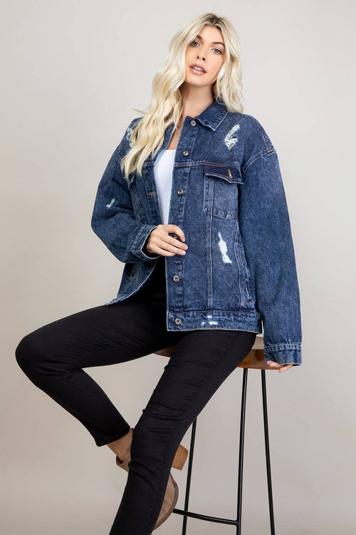 Woman wearing a blue denim jacket and black pants on a beige background
