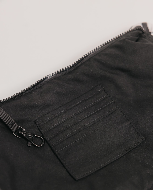Close-up of a black zippered pouch with a pocket on a light gray background