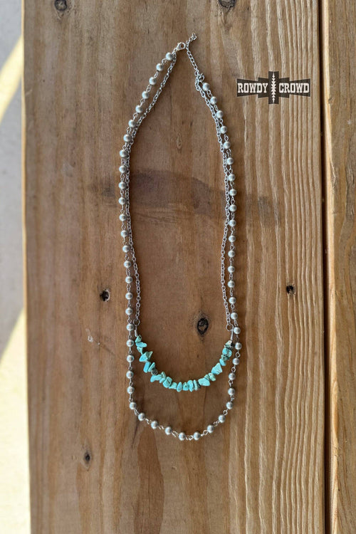 Necklace with turquoise and pearl beads on a wooden surface, featuring the brand 'Rody & Crowd'.