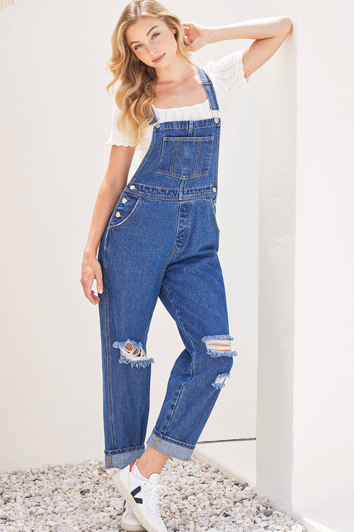 Woman wearing blue denim overalls with a white background