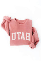 Pink sweatshirt with 'UTAH' printed on it against a white background