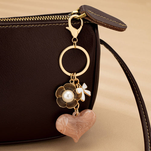 Keychain with heart and floral design on a brown leather bag