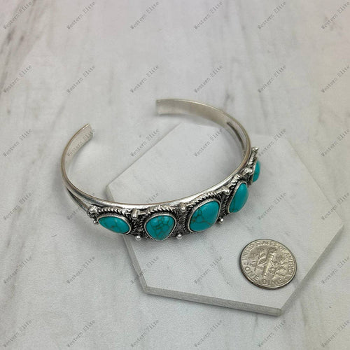 Silver bracelet with turquoise stones on a textured surface