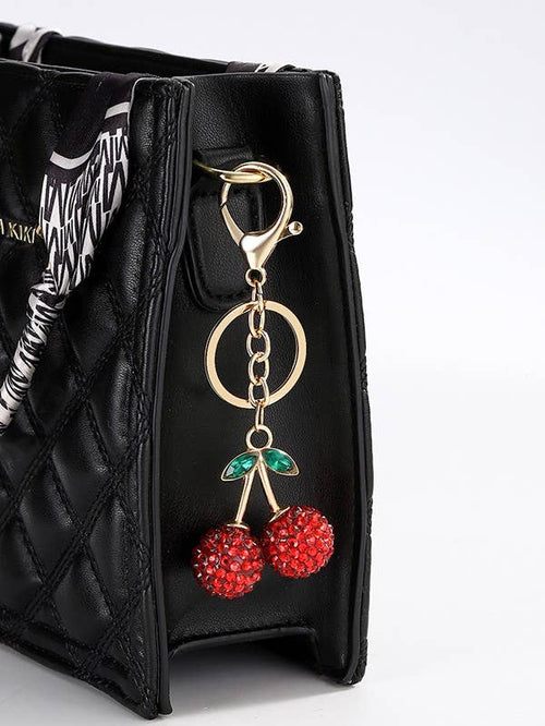 Black handbag with a keychain featuring red cherries on a white background