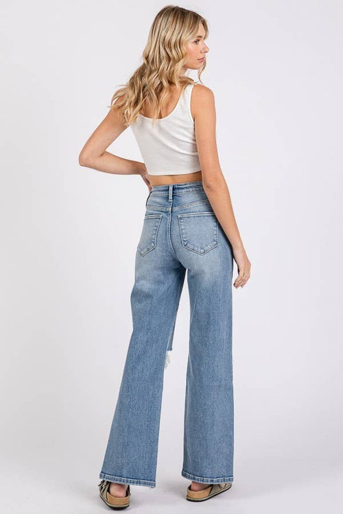 Woman wearing light blue jeans and a white top on a white background