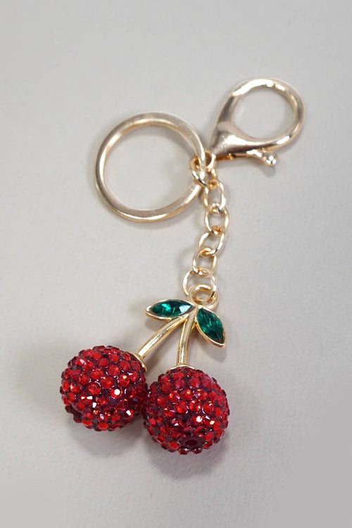 Keychain with red cherries and gold stem on a gray background