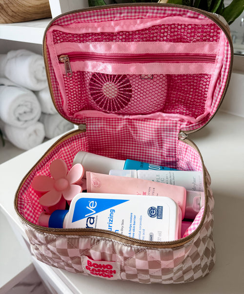 Open pink toiletry bag with skincare products on a white surface