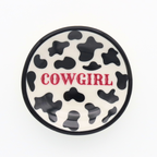 Round ceramic coaster with cow print and 'Cowgirl' text on a white background