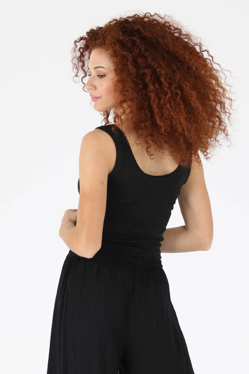 Woman wearing a black sleeveless top and black pants on a white background