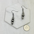 Pair of silver beaded earrings on a hexagonal marble tile with a coin for scale.