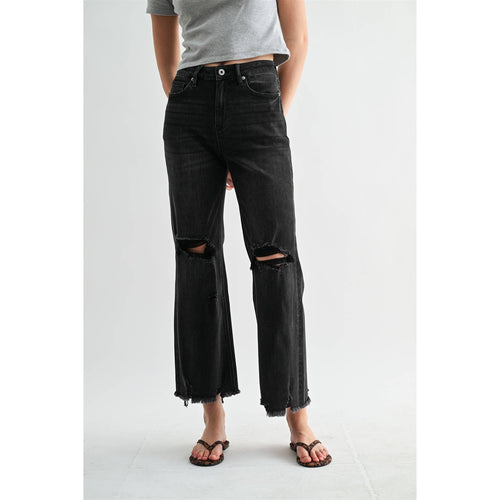 Person wearing black distressed jeans on a white background