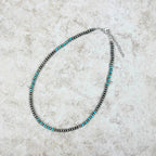 Necklace with black and turquoise beads on a light gray surface