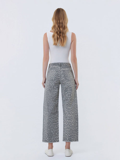Woman wearing a white sleeveless top and gray leopard print pants on a white background