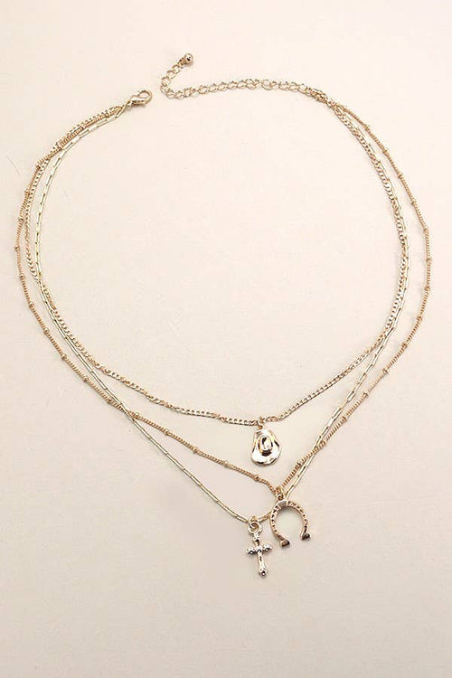 Layered gold necklaces with various charms on a beige background