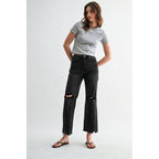 Woman wearing a gray t-shirt and black ripped jeans on a white background