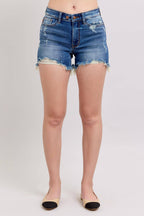 Person wearing blue denim shorts on a plain background