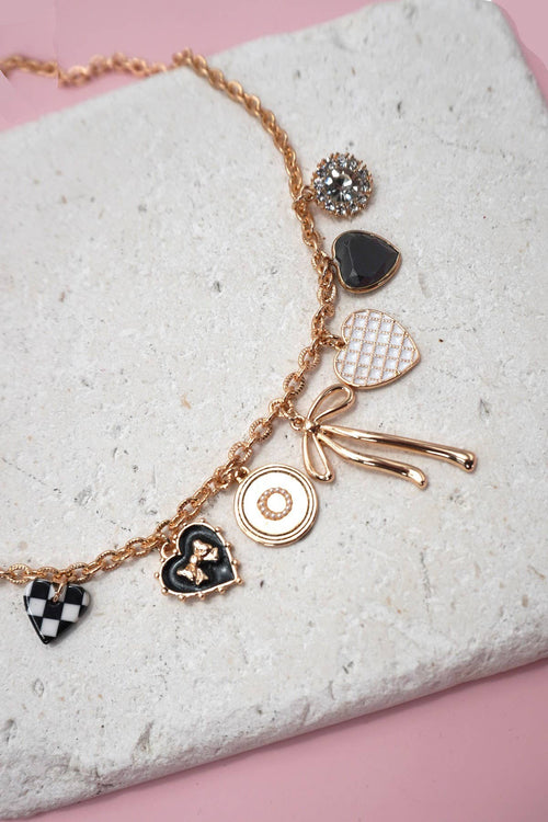 Necklace with various charms on a textured surface with a pink background