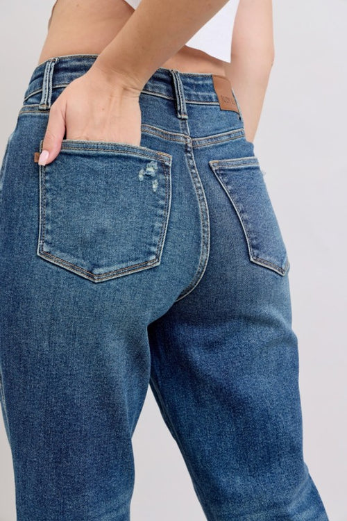 Blue jeans worn by a person on a plain background