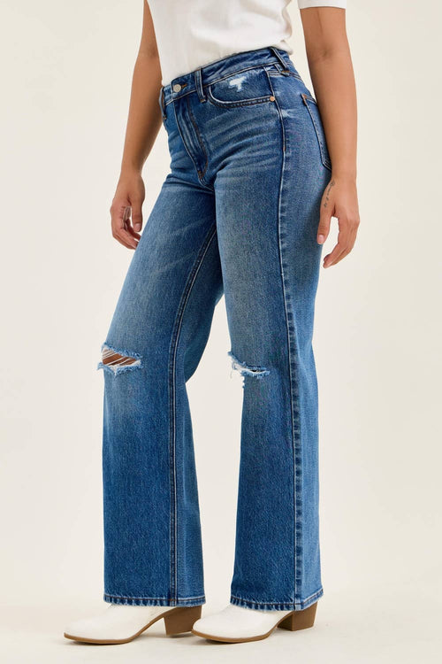 Person wearing blue distressed jeans on a plain background