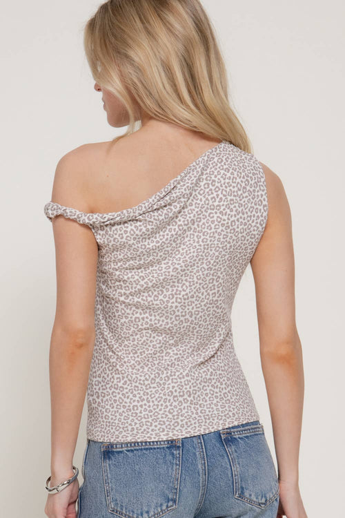 A woman shown from the back wearing a one-shoulder leopard print top and blue jeans against a plain light background.