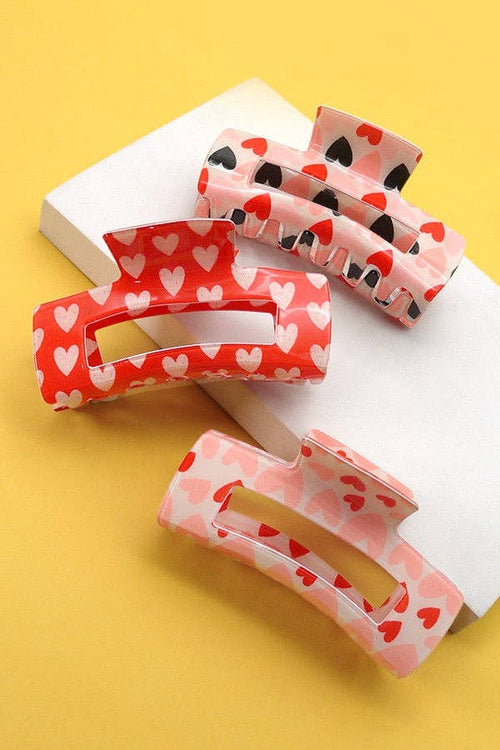 Three hair clips with heart patterns on a yellow background