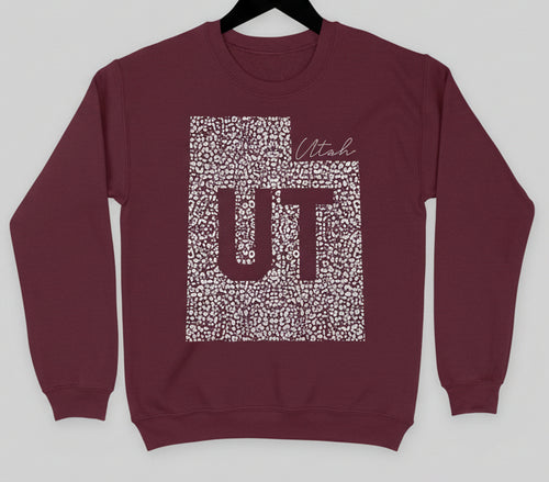 Maroon sweatshirt with 'UT' design on a hanger against a white background