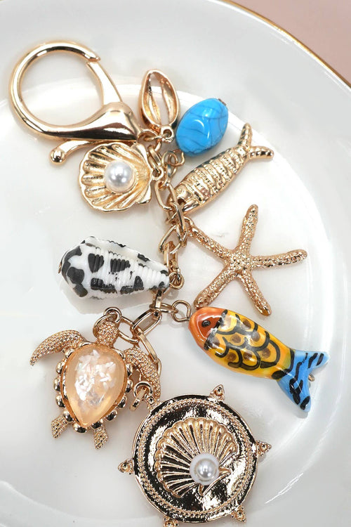 Keychain with various charms including a turtle, fish, and starfish on a white plate.